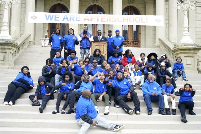 Bobby Christian with students and staff under a WE ARE AFTERSCHOOL banner on the Michigan State Capitol steps