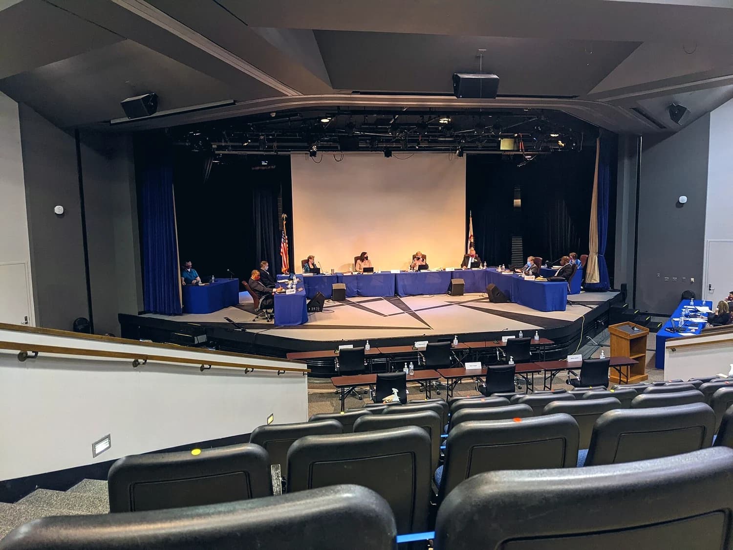 A school board meeting in session, with rows of empty public seats