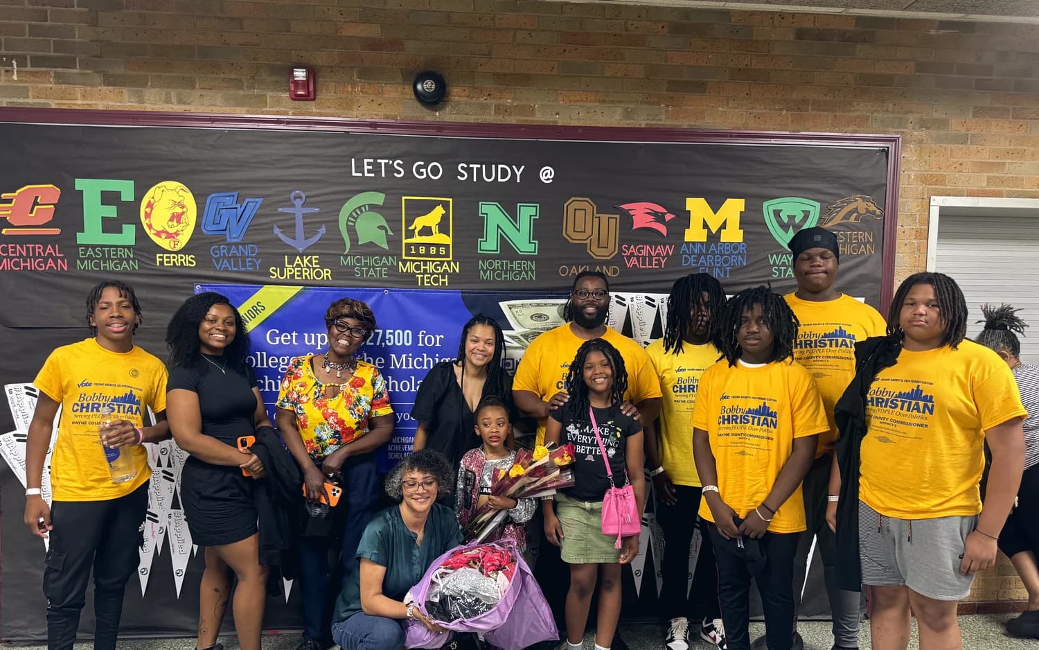 A college access and scholarship event with students and Michigan university logos