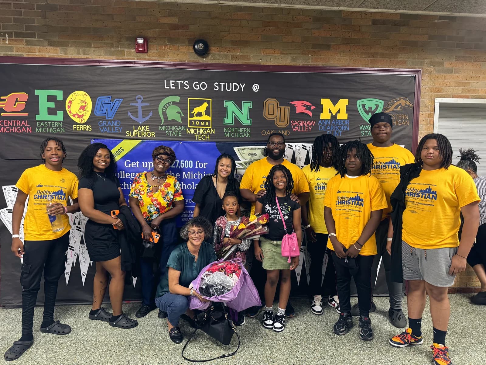 A college access and scholarship event with students and Michigan university logos